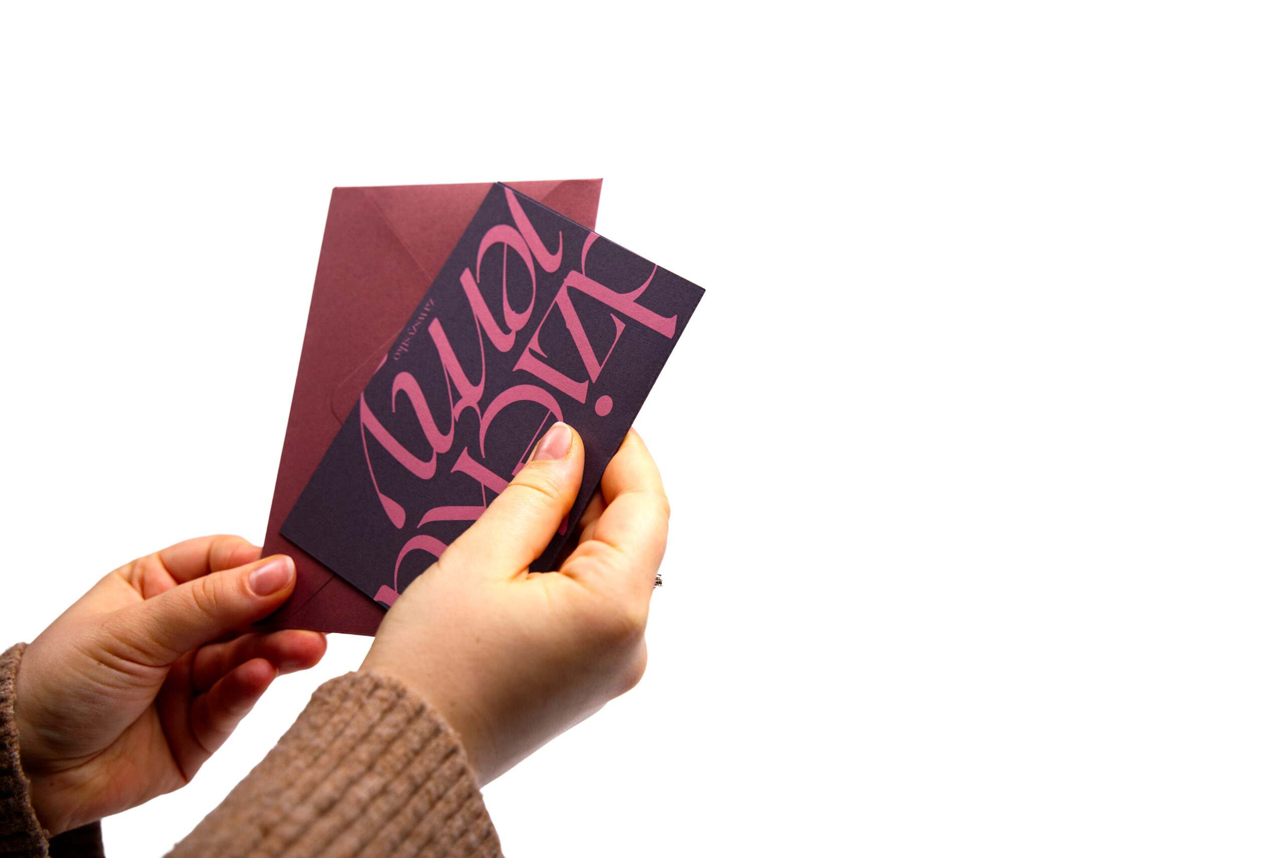 Grafitowa kartka z podziękowaniem Dziękujemy z różowym napisem trzymana w dwóch dłoniach z bordową kopertą